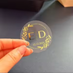 Small round gold logo sticker being peeled from sheet